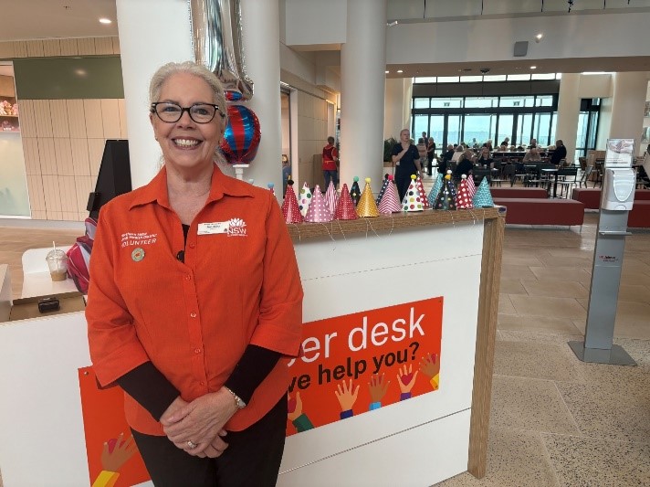 A lady volunteer standing at the front of the hospital desk